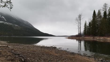 Foggy-Cloudy-Day-Lakeside-with-Pine-Trees-and-Snowy-Mountain-View-during-the-Afternoon-at-St
