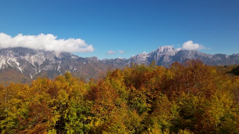 Berglandschaft-Im-Herbst-Mit-Leuchtenden-Farben-Von-Gelben-Und-Roten-Bäumen,-Weißen-Wolken-Und-Blauem-Himmel