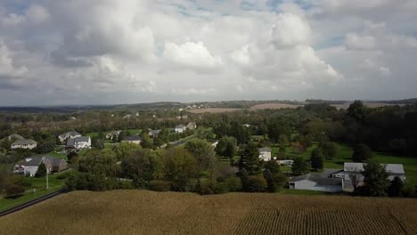 Aerial-view-of-a-countryside-village-and-cornfields,-on-a-cloudy-day