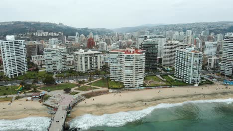 Aerial-establishing-shot-of-Viña-del-Mar-city-with-mountains-and-cloudy-sky-behind