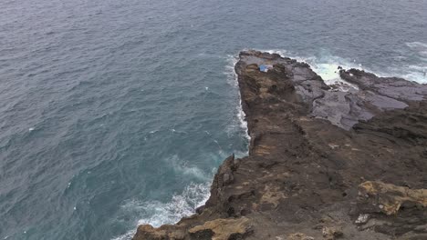Aerial-view-of-cliff-revealing-rocky-point-in-Hawaii-tracking-forward