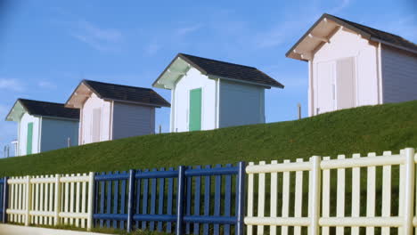 Colorful-Beach-Huts-at-the-coast-on-grass-with-fence