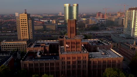 Aerial-pan-showing-sunrise-illuminating-the-Inktpot-building-with-UFO-resting-on-its-facade-flanked-by-modern-skyscraper-buildings