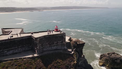 Aerial-view-Tourists-exploring-the-Nazaré-Lighthouse-with-Seascape-as-Background
