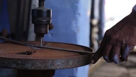 Hand-Des-Menschen-Bei-Der-Arbeit-Mit-Alten-Rostigen-Bohrmaschinen-Im-Labor-Des-Dorfes-Sakhi-Saheli,-Rajasthan