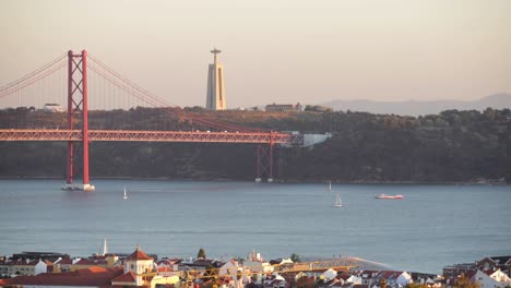 Fantastischer-Moment,-Um-Cristo-Rei-In-Einem-Sonnenuntergang-Von-Lissabon-Aus-Zu-Sehen,-Während-Die-Boote-Den-Fluss-überqueren