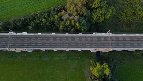 Top-view-of-train-tracks-on-a-bridge-with-surrounding-landscape