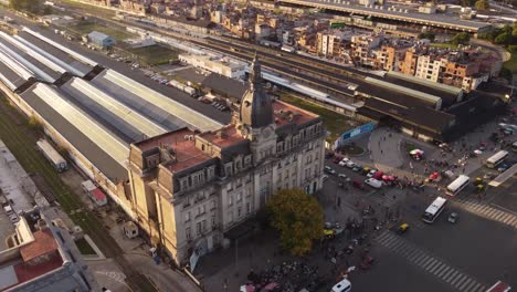 Aerial-view-of-traffic-on-road,driving-buses-in-front-of-train-station-with-historic-building-during-sunset---Rush-Hour-time-in-Retiro-district-of-Buenos-Aires,Argentina