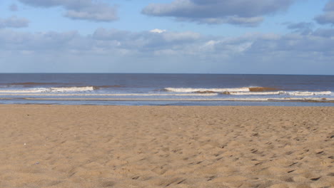 Waves-on-the-beach-in-the-UK-with-clouds-and-a-blue-sky