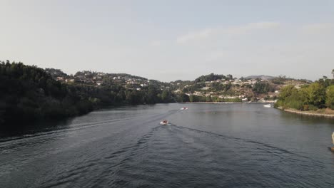 Fly-over-Rio-Douro,-motorboats-cruising-the-calm-flow-of-water,-Castelo-de-Paiva,-Portugal