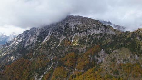 Beautiful-mountain-with-high-peak-under-clouds-and-colorful-forest-in-Autumn