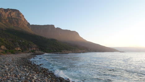 Wellen-An-Der-Felsigen-Küstenlinie-Des-Strandes-Mit-Dem-Berg-Der-Zwölf-Apostel-Im-Hintergrund-In-Kapstadt,-Südafrika