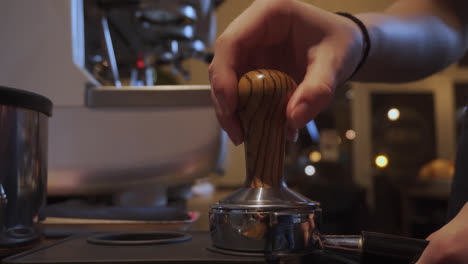 Barista-tamping-coffee-grinds-inside-a-small,-dimly-lit-cafe-bar