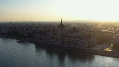 Revealing-drone-shot-into-the-sun,-of-the-Hungarian-Parliament-Building-in-Budapest-Hungary