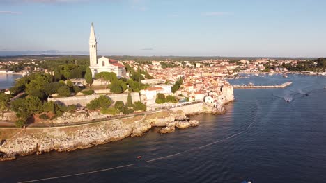 Rovinj-at-Istria,-Croatia---Aerial-Drone-View-of-the-Peninsula-with-Church-Tower,-Boulevard,-Colorfol-Houses-and-Port-during-sunset
