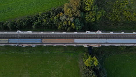 Top-view-of-train-tracks-on-a-bridge-with-surrounding-countryside-and-a-passing-train