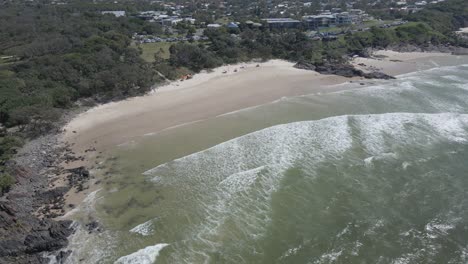 Waves-Splashing-On-The-Shore-And-Cliff-At-Cabarita-Beach,-New-South-Wales,-Australia---aerial-pullback