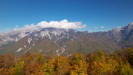 Follaje-Dorado-De-Los-árboles-Y-El-Fondo-De-La-Montaña-De-Los-Alpes,-Nubes-Y-Cielo-Azul