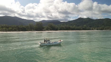 small-fishing-motor-boat-of-the-coast-of-Thai-tropical-island-with-mountains,-blue-sky
