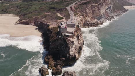 Aerial-high-angle-view-of-clifftop-Fortress-of-Saint-Michael-the-Archangel-and-Nazare-lighthouse