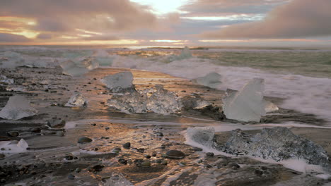 Close-up-shot-of-black-sandy-beach-with-icebergs-flooded-by-waves-of-North-Atlantic-Ocean