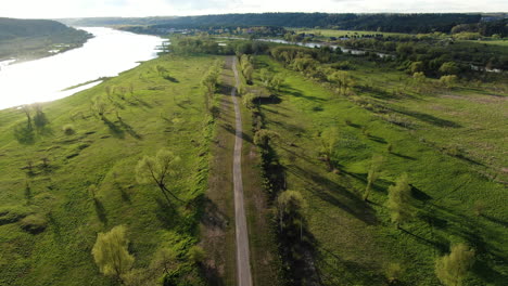 Empty-modern-bicycle-pathway-in-green-landscape-near-river,-aerial-drone-view
