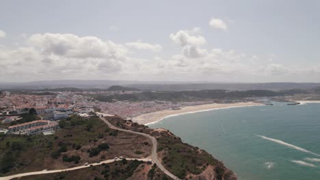 Einzigartiger-Luftpanoramablick-Auf-Das-Vorgebirge-Von-Nazare-Und-Den-Strand-Im-Hintergrund,-Portugal