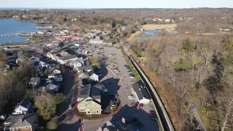 Aerial-push-forward-parallel-with-railroad-tracks-and-a-small,-downtown-street-in-a-coastal-new-england-town