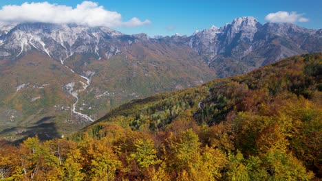 Panoramic-cinematic-shot-of-Autumn-scene-with-yellow-red-trees-and-mountains-in-sunlight