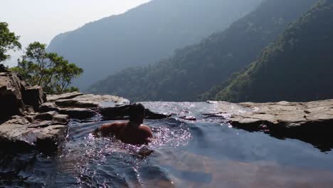man-swimming-in-natural-swimming-pool-at-mountain-cliff-from-top-angles