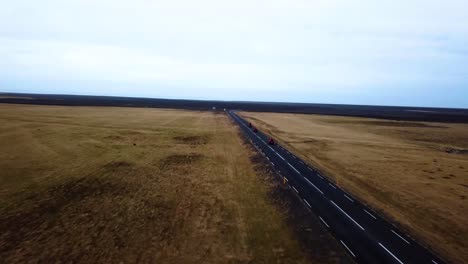 Aerial-view-of-red-quad-bikes-speeding-on-a-empty-straight-road-through-Iceland-highlands