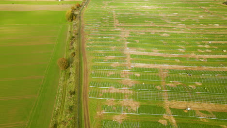 Left-to-right-photovoltaic-farm-construction-site,-green-field-prepared-for-solar-power-plant-construction---aerial-top-down