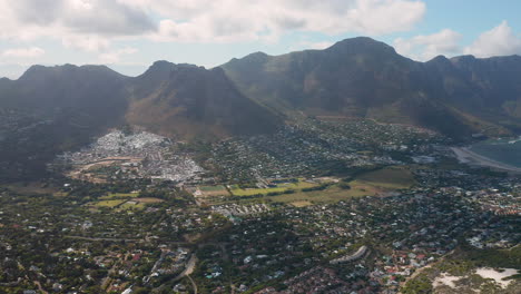 Panoramic-View-Of-sandy-bay,-Houtbay-in-the-distance-In-South-Africa---revolving-aerial-shot