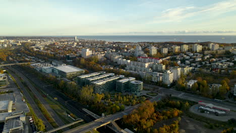 Luftaufnahme-Des-Modernen-Gebäudes-Des-Pommerschen-Technologieparks,-Der-Wohngebietsblöcke-Und-Der-Ostsee-Im-Hintergrund-Bei-Sonnenaufgang-In-Polen