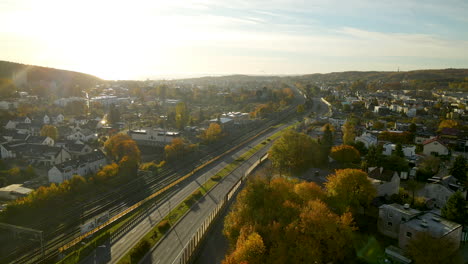 Flying-back-along-winding-highway-and-railway-road-in-Autumn-color-Gdynia-cityskyline-on-bright-sunrise