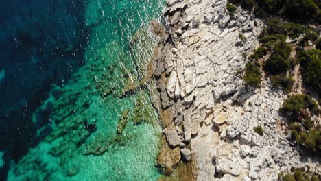 Stony-Shoreline-On-The-Secluded-Bay-At-Emplisi-Beach-Revealed-Fiskardo-Town-In-Kefalonia,-Ionian-Islands,-Greece