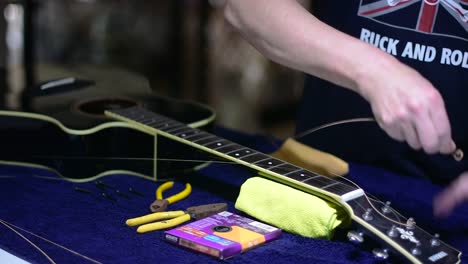 Restringing-and-cleaning-a-beautiful-black-single-cutaway-accoustic-guitar---unwinding-the-strings-from-the-machine-heads