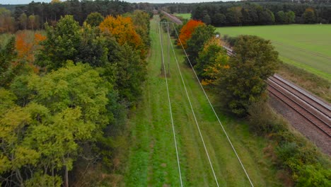 Aerial:-Thetford-forest-with-railway-track-and-electric-line-at-Brandon,-England---drone-flying-shot
