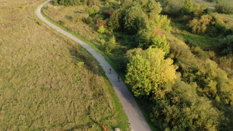 Radfahrerfahrt-Auf-Asphaltstraße-In-Majestätischer-Ländlicher-Landschaft-Litauens,-Luftdrohnenansicht