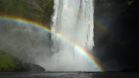Powerful-Stream-Flowing-From-Steep-Rocky-Cliffs-With-Rainbow-In-Skogafoss,-Skogar,-Iceland
