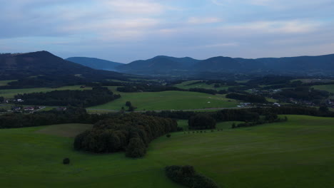 Luftaufnahme-Einer-Landschaft-Voller-Hügel-Am-Späten-Nachmittag-Und-Berge-Im-Hintergrund