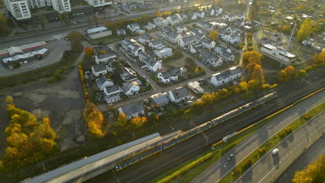 Aerial-top-down-shot-of-public-train-passing-housing-area-district-in-Gdynia-during-sunrise
