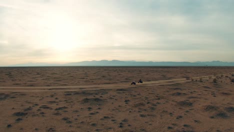 Fahren-Sie-Mit-Dreirädrigen-Dreirädern-Auf-Einem-Schotterweg-In-Der-Mojave-Wüste---Atemberaubende-Luftaufnahme-Bei-Sonnenuntergang