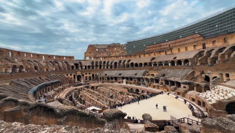 Pov-Vorwärts-Zeigt-Das-Epische-Historische-Italienische-Kolosseum-In-Rom-Während-Des-Bewölkten-Tages---Breite-Aufnahme-Zeigt-Viele-Touristen,-Die-Das-Wahrzeichen-Besuchen---Das-Größte-Stehende-Amphitheater-Der-Welt-Heute