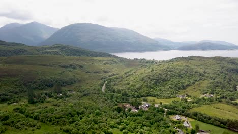 Aerial-forward-wide-view-of-stunning-green-Scottish-Highlands-with-mountains-and-lakes