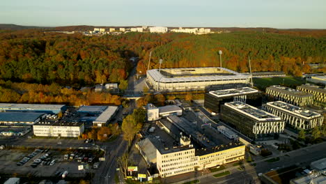 Edificios-De-Fábrica-Y-Estadio-De-Fútbol-Frente-Al-Colorido-Bosque-En-La-Ciudad-De-Gdynia,-Polonia