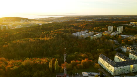 Aerial-Panning-over-Beautiful-Colorful-Autumn-Forest-in-Gdynia-next-to-Apartment-buildings-at-sunrise