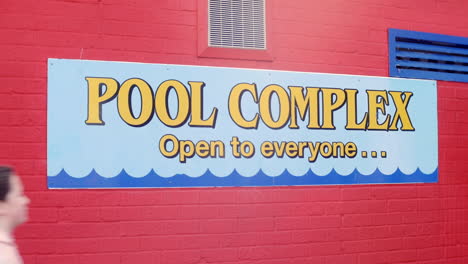 Girl-walks-past-a-swimming-pool-sign