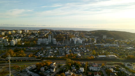 Aerial-flying-over-Gydnia-City-Autumn-Skyline-with-Residential-Buildings-and-Roads-in-October-at-sunrise,-Baltic-sea-on-background