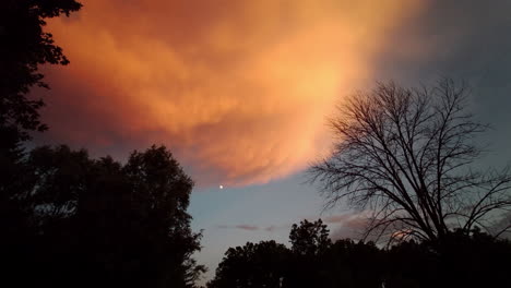 Pan-across-evening-sky-with-moon-and-dramatic-storm-clouds-at-sunset